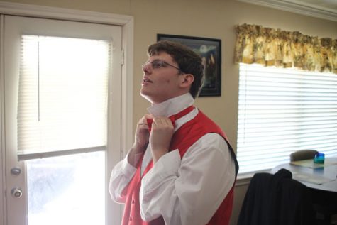 Garrett Baas, 12, ties a bright red bow tie.