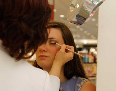 A makeup consultant applies black eyeshadow onto Makayla,12, eyelids.